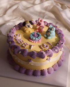 a yellow and purple cake sitting on top of a white tablecloth covered table cloth