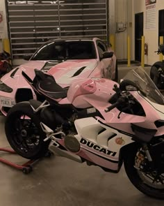 a pink and white motorcycle parked next to a car in a garage with other motorcycles