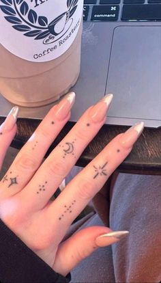 a woman's hand with tattoos on it next to a coffee cup