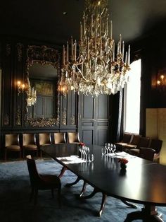 an elegant dining room with chandelier and large wooden table in front of dark wood paneled walls