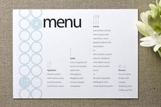 a menu with flowers on the table next to it