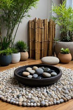 a bowl filled with rocks sitting on top of a wooden floor next to potted plants