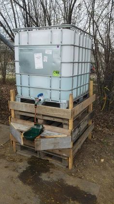 a large container sitting on top of a wooden pallet next to a green bucket