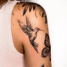 a woman with a tattoo on her arm has a hummingbird and butterflies around her shoulder