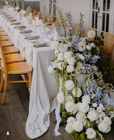 a long table with white and blue flowers is set up for an outdoor wedding reception