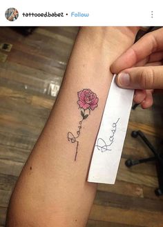 someone is holding up their arm with a rose tattoo on the left side of it