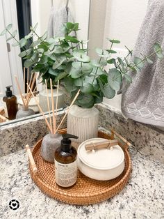 a bathroom counter with soap, lotion and plants on it