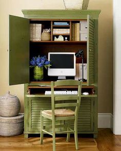 a desk with a computer on top of it in front of a green cabinet and chair