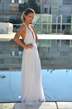 a woman standing in front of a pool wearing a white dress