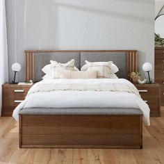 a bed with white sheets and pillows in a room