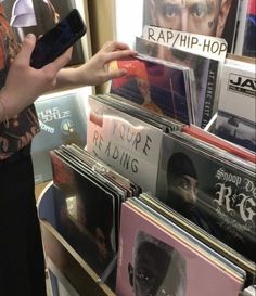 a person holding up a cell phone in front of records