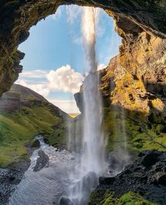 a waterfall is seen through an opening in the ground