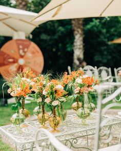 there are many vases with flowers on the table in front of some umbrellas