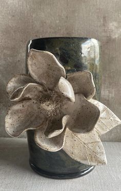 a ceramic flower sitting in a black vase