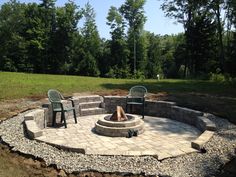 an outdoor fire pit surrounded by chairs