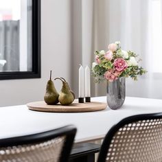 two pears on a table with flowers and candles