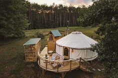 a yurt in the middle of a forest with trees around it and a deck