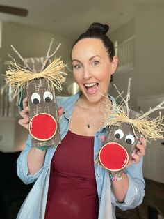 a woman holding up two reindeer masks with hay on them