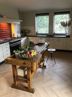 a kitchen with an island made out of wooden planks and bowls of fruit on it