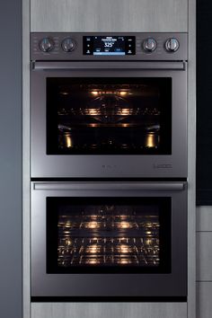 two stainless steel ovens side by side with the door open and lights on them