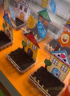 some little houses that are sitting in the dirt on a table with orange cloths