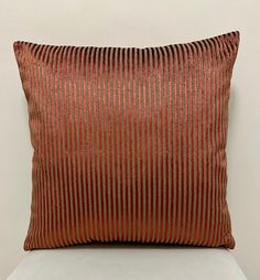 a red and gold striped pillow on a white chair