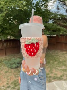 a person holding up a cup with a strawberries on it