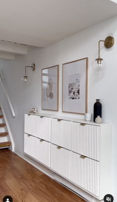 a room with white furniture and pictures on the wall next to a stair case in front of a window