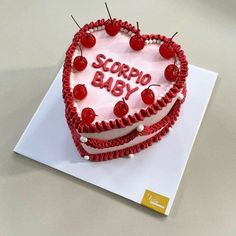 a heart shaped cake with the words scorppo baby on it and cherries