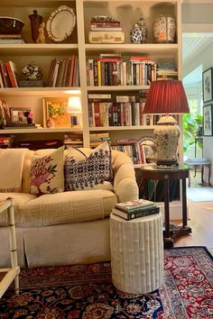 a living room filled with lots of furniture and bookshelves full of books on top of them