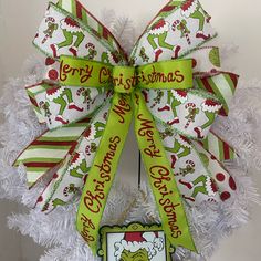 a christmas wreath hanging on the side of a white tree with green and red ribbon