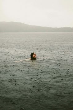 a person floating in the water on top of a body of water with mountains in the background