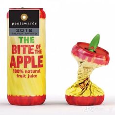 an apple is wrapped in gold foil and sitting next to a bottle of fruit juice