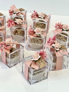 there are many cupcakes in clear boxes with pink bows on them and flowers