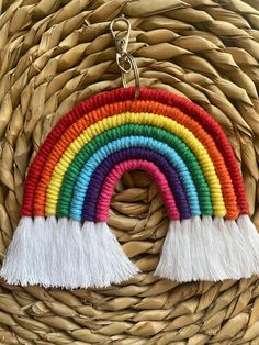 a rainbow keychain with tassels hanging from it's side on a wicker basket