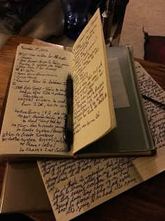 two notebooks with writing on them are sitting on a table next to a pen