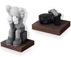 an elephant figurine sitting next to a camera on a wooden stand with two other items