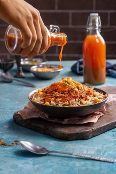 someone is pouring sauce over a bowl of food