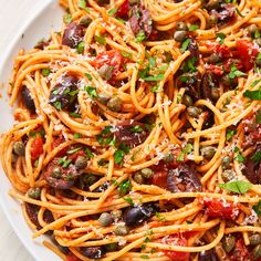 a white plate topped with spaghetti and olives