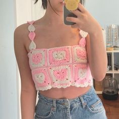 a woman is taking a selfie with her cell phone wearing a crocheted crop top