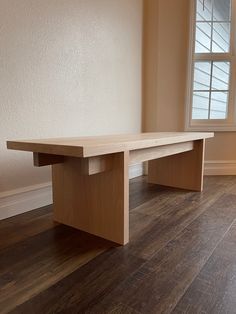 a wooden bench sitting in front of a window on top of a hard wood floor