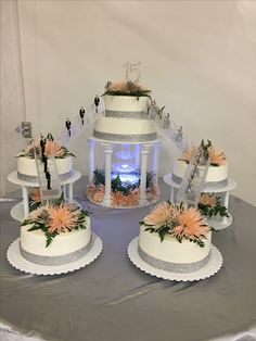 three tiered wedding cake sitting on top of a table with flowers in the middle