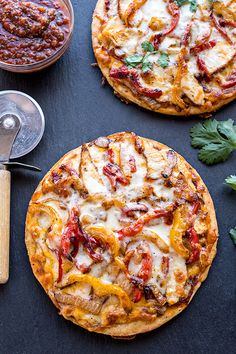 two pizzas sitting on top of a black table