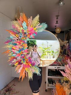 a woman taking a selfie in front of a mirror with colorful feathers on it