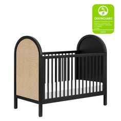 a black crib with an oval shaped bed in the middle and a greenguard sticker above it