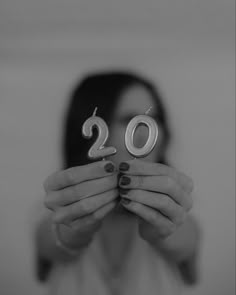 a woman holding two candles in front of her face with the number 20 on it