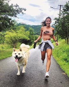 a woman is running with her dog on a leash