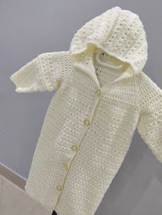 a crocheted white coat hanging on a clothes rack with the hood pulled up