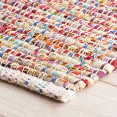 a multicolored rug is laying on a wooden floor with a white table top