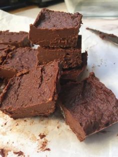 a pile of chocolate brownies sitting on top of a white paper towel next to a knife